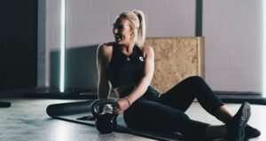 Mujer entrenado con kettlebell en casa - Entrenador Wellness