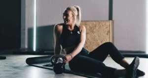 Mujer entrenado con kettlebell en casa - Entrenador Wellness