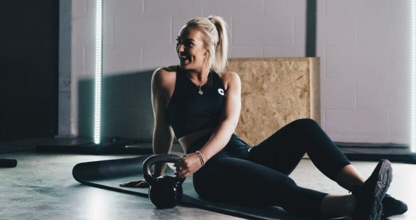 Mujer entrenado con kettlebell en casa - Entrenador Wellness